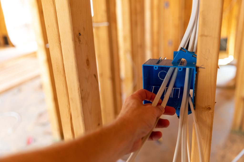 Hand working on electrical wires in new home construction